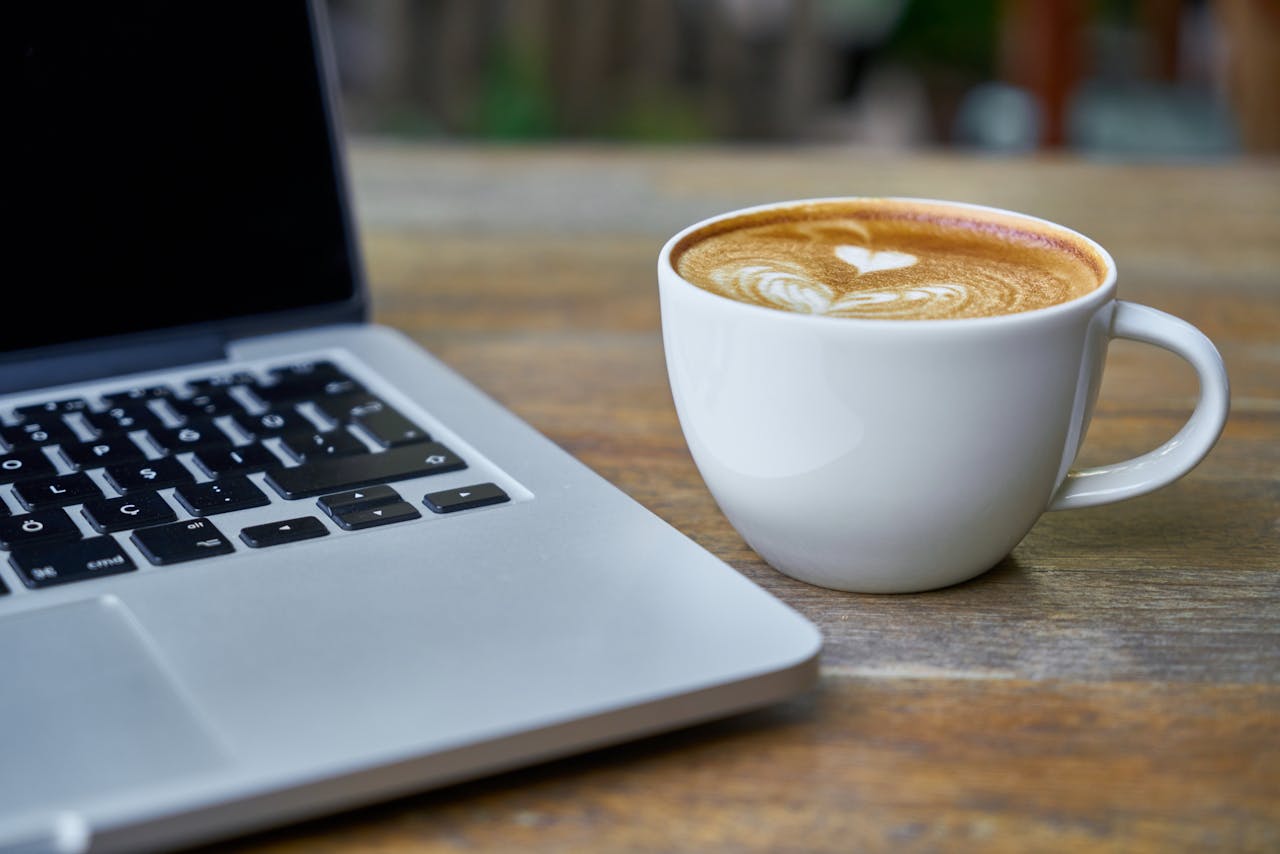 Teacup of Latte Beside Macbook Pro